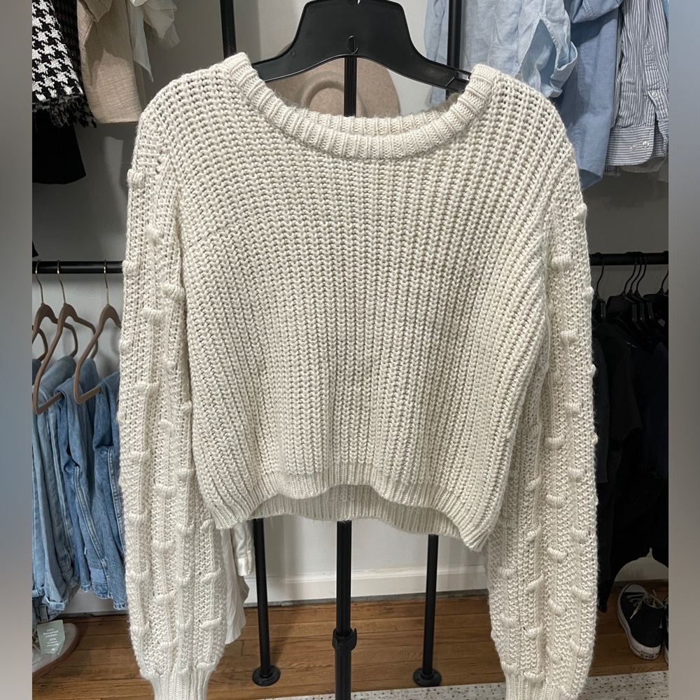 White sweater with dot detail on the sleeve
